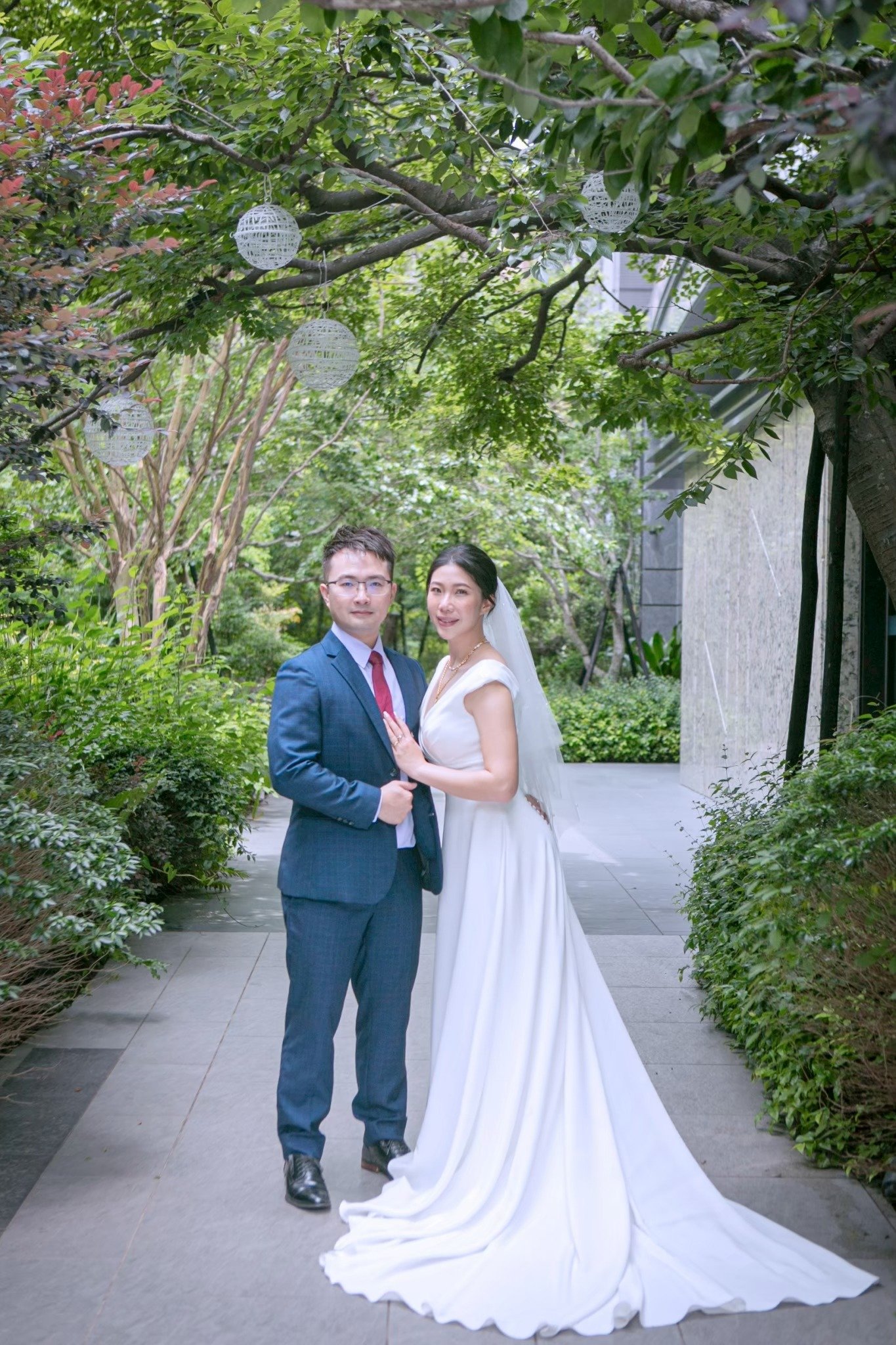 Yulia 與 Tino 站在綠蔭下的婚紗照